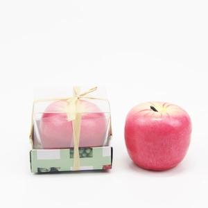 Vista detallada de vela de manzana roja artificial en caja de regalo con lazo beige