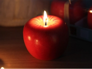 Primer plano de una vela de manzana roja realista con mecha encendida para fiestas