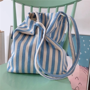 Blue and white striped canvas tote bag detail on a vintage chair in a cozy setting