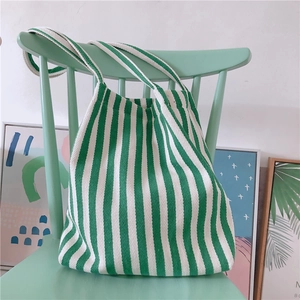 Artistic detail of thick striped canvas tote bag hanging on a mint green wooden chair