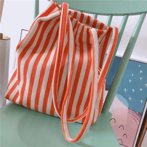 Close-up of a striped canvas tote bag in orange and white leaning on a green wooden chair