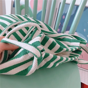 Close-up of green and white striped canvas tote bag on a chair showing durable texture
