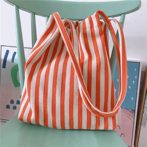 Detail of orange and white striped canvas tote bag resting on a wooden mint green chair