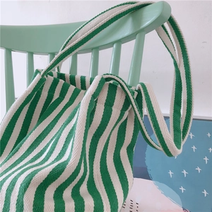 Detail of green striped canvas tote bag texture hanging on a mint wooden chair