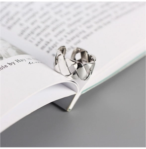 Close-up of S925 sterling silver woven ring on an open book with elegant soft lighting