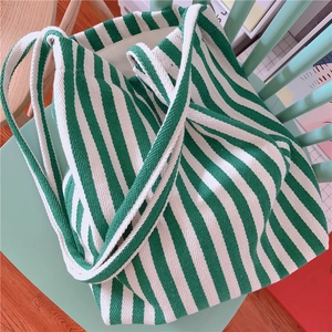 Detail of green and white striped canvas tote bag resting on a light green wooden chair