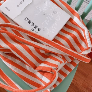 Detailed texture of thick orange striped canvas tote bag on a rustic wooden chair