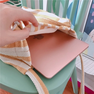Detail showing a 13-inch laptop being placed into a yellow striped canvas shoulder bag