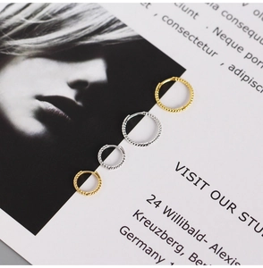 Detailed view of gold and silver twisted rope hoop earrings on a fashion card