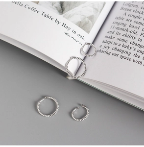 Detail of S925 sterling silver twist hoop earrings in two sizes on an aesthetic magazine