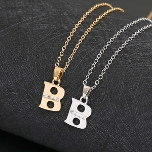Close-up of gold and silver letter B pendants with sparkling zircon crystal stones