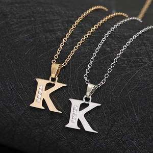 Macro detail of gold and silver initial K pendants with sparkling cubic zirconia stones