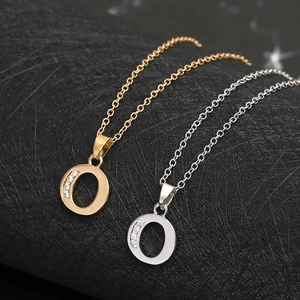Detailed view of gold and silver letter O pendants with inlaid diamonds on a curved base
