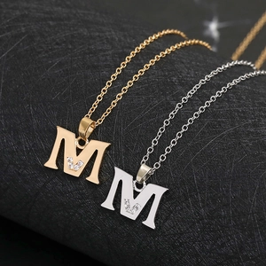 Detailed macro view of gold and silver initial M necklaces with zircon stone accents