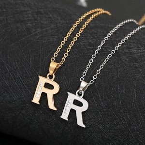 Detail of R letter pendant necklace in gold and silver finish with sparkling zircons