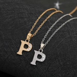 Macro shot of gold and silver letter P pendants with cubic zirconia inlay on black background