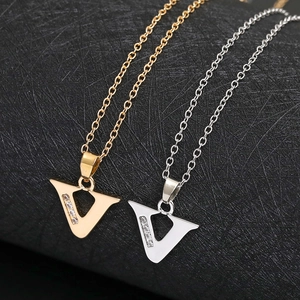 Macro shot of V-shaped gold and silver necklaces with crystals on brushed black surface