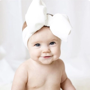 Soft white waffle knit baby headband featuring an oversized decorative bow knot