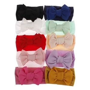 Flat lay of 10 multicolor waffle texture baby bow headbands on high elastic nylon bands