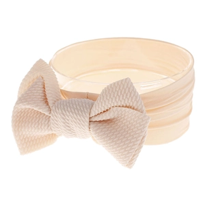 Detailed close-up of cream knit waffle fabric baby headband with large soft bow