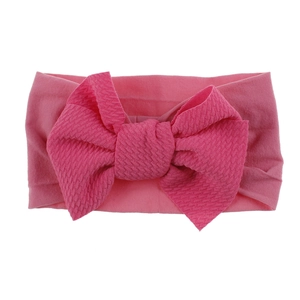 Detail of soft ribbed nylon baby headband with a large bright pink knotted bow