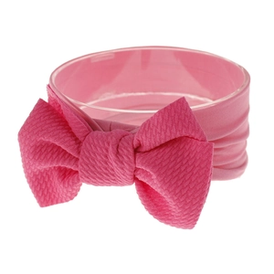 Detail of bright pink nylon baby headband with large bow and waffle knit texture