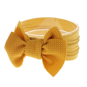 Detail of mustard yellow waffle knit baby headband with a large decorative bow