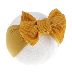 Detail of soft mustard yellow waffle knit bow headband for infants on white props