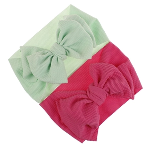 Detail view of mint green and magenta baby bow headbands in soft textured fabric.