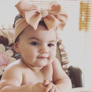 Close-up of baby wearing a large peach bow headband in soft waffle textured fabric