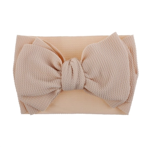 Detail showing soft skin-pink waffle texture fabric bow on elastic baby headband