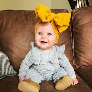Close-up detail of a cute baby wearing a large yellow textured fabric bow headband