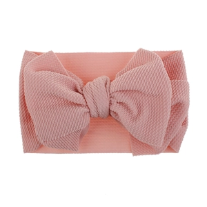 Detailed macro view of a soft pink textured fabric baby headband with a large bow