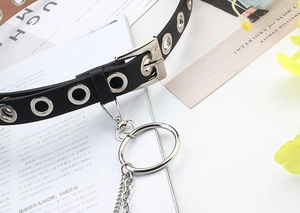Detail view of a black punk PU leather belt with silver eyelets, metal rings, and chain