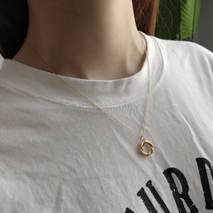 Detail of twisted gold ring pendant on a fine necklace chain shown on a model