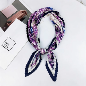 Détail d'un foulard plissé en soie avec imprimé floral bleu et violet noué en nœud