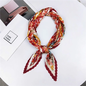Détail d'un foulard plissé à motifs floraux rouges, jaunes et bleus sur fond blanc