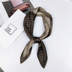 Gros plan d'un foulard en soie plissé aux motifs paisley et pois en marron et beige
