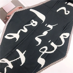Gros plan détaillé montrant la texture du tissu plissé noir et le motif de calligraphie arabe blanc