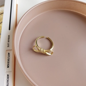 Macro view of golden bow tie ring with pavé cubic zirconia on minimalist tray