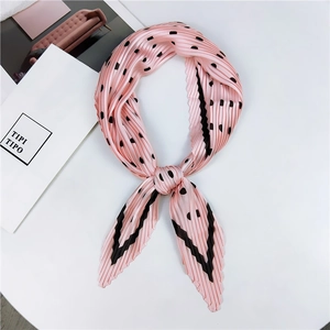 Détail d'un foulard plissé rose à pois noirs et motifs géométriques avec un nœud élégant
