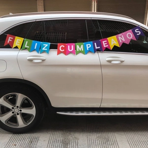 Spanish Feliz Cumpleaños birthday banner hung on a white SUV for outdoor party decoration