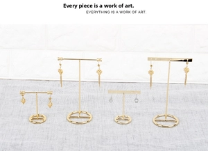 Detail of four gold T-bar earring stands with round bases for studs and hooks