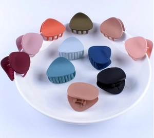 Assorted matte finish triangle hair claws in multiple colors arranged in a white plate