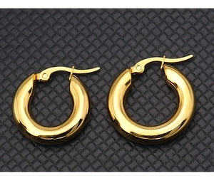 Close-up of polished gold-plated thick hoop earrings on a black leather background