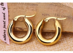 Macro shot of thick gold-plated stainless steel hoop earrings with polished mirror finish