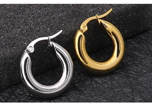 Macro shot of polished gold and silver thick hoop earrings with secure click closure