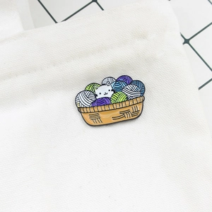 Close-up of a cute cat in basket enamel pin attached to a white canvas bag fabric