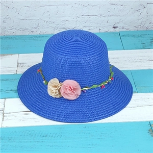 Dark blue straw sun hat with decorative pink flower garland and wide brim for summer