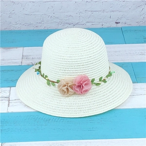 White woven straw hat with green leaf vine and fabric flowers for summer beach vacations